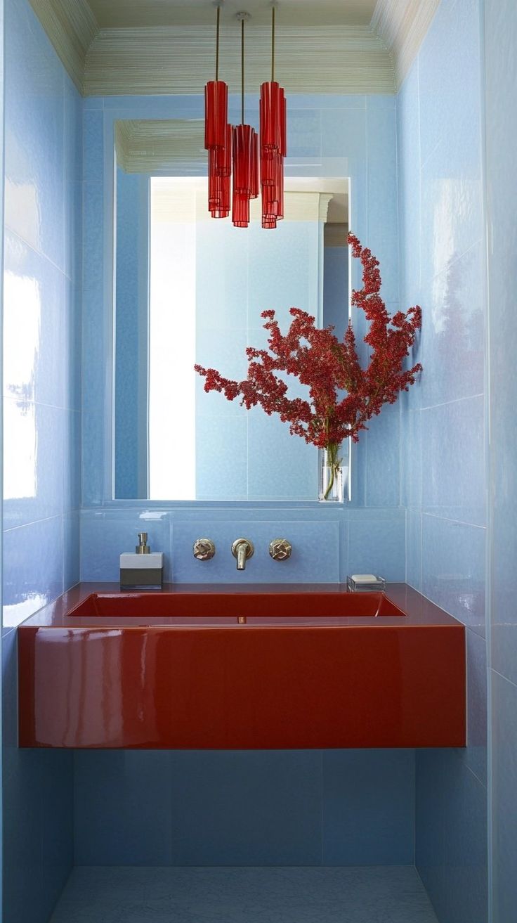 a red sink in a blue bathroom under a large mirror with hanging lights above it