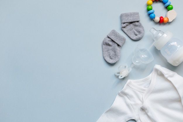 baby clothes and accessories laid out on a light blue background with space for the text