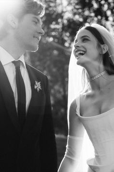 the bride and groom are laughing together in black and white photo with sunlight coming through trees