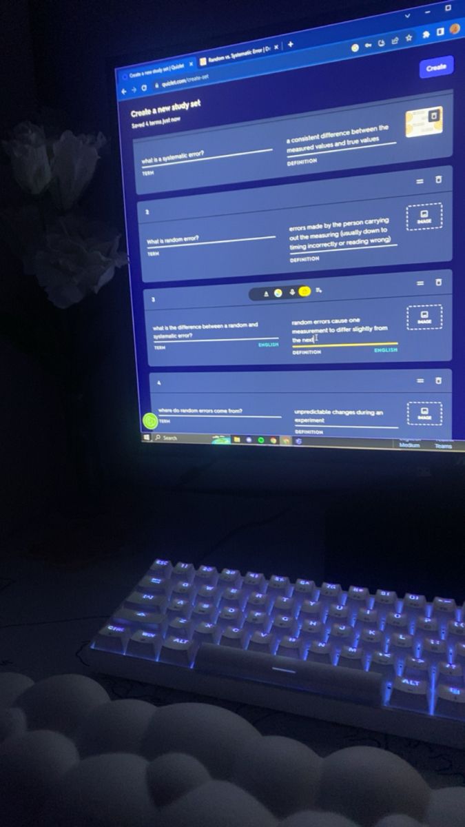 a computer keyboard and monitor lit up in the dark with blue light shining on it