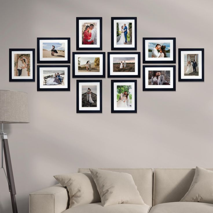 a living room with a white couch and many pictures on the wall above it in black frames