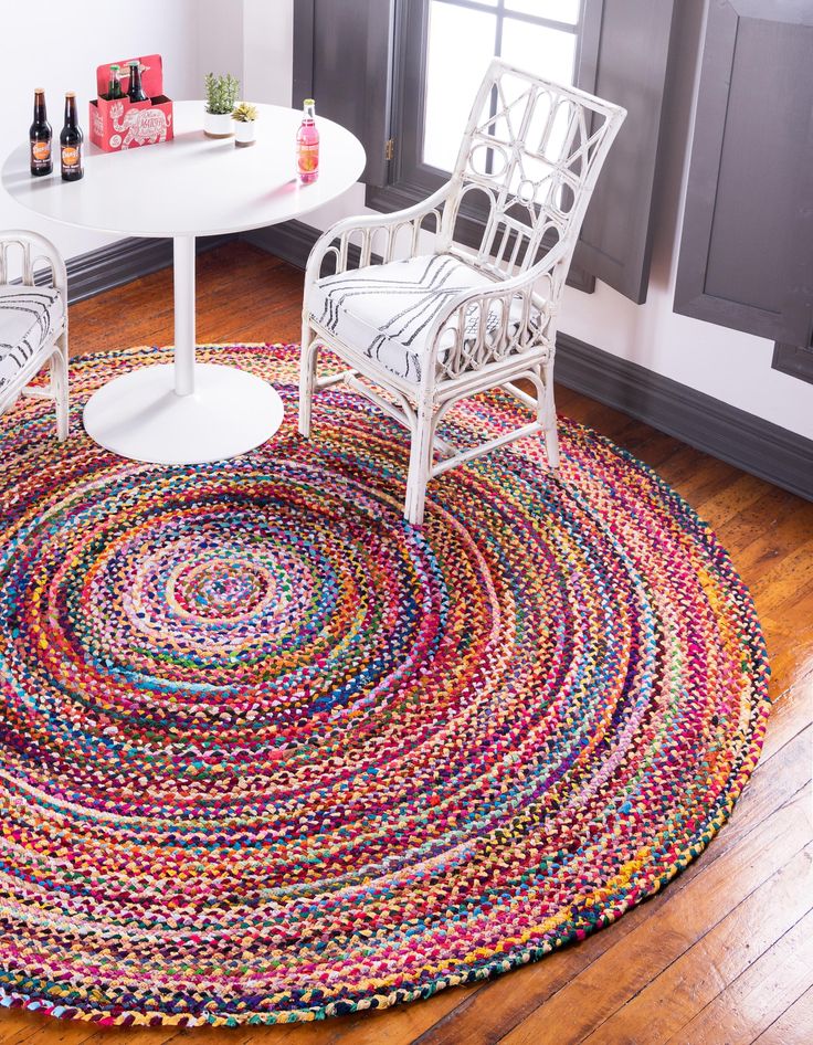 a round rug with two chairs and a table in the middle, on top of a hard wood floor