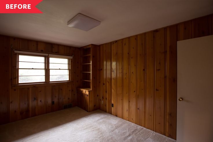 an empty room with wood paneling on the walls and carpeted floor, in front of a window