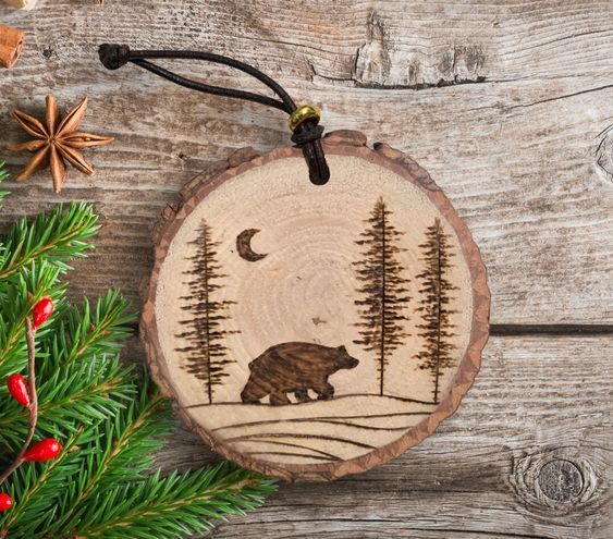 a wooden ornament with an image of a bear and pine trees on it