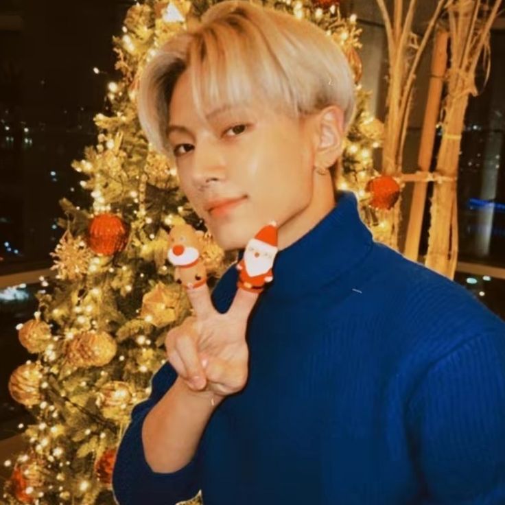 a person standing in front of a christmas tree holding two candy lollipops