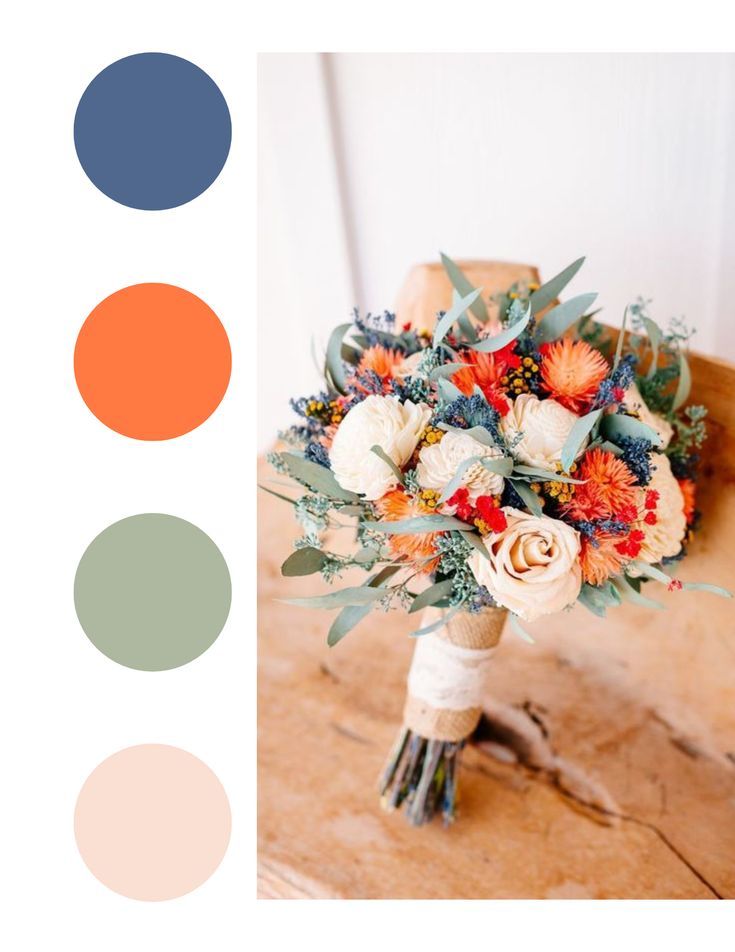 a bridal bouquet with orange, white and blue flowers in it on a wooden table