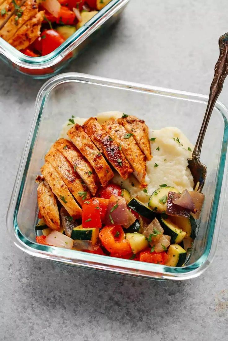 two glass containers filled with chicken, veggies and mashed potatoes next to each other