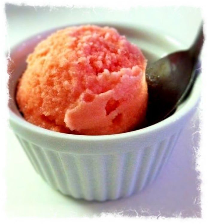 a bowl filled with ice cream sitting on top of a white table next to a spoon