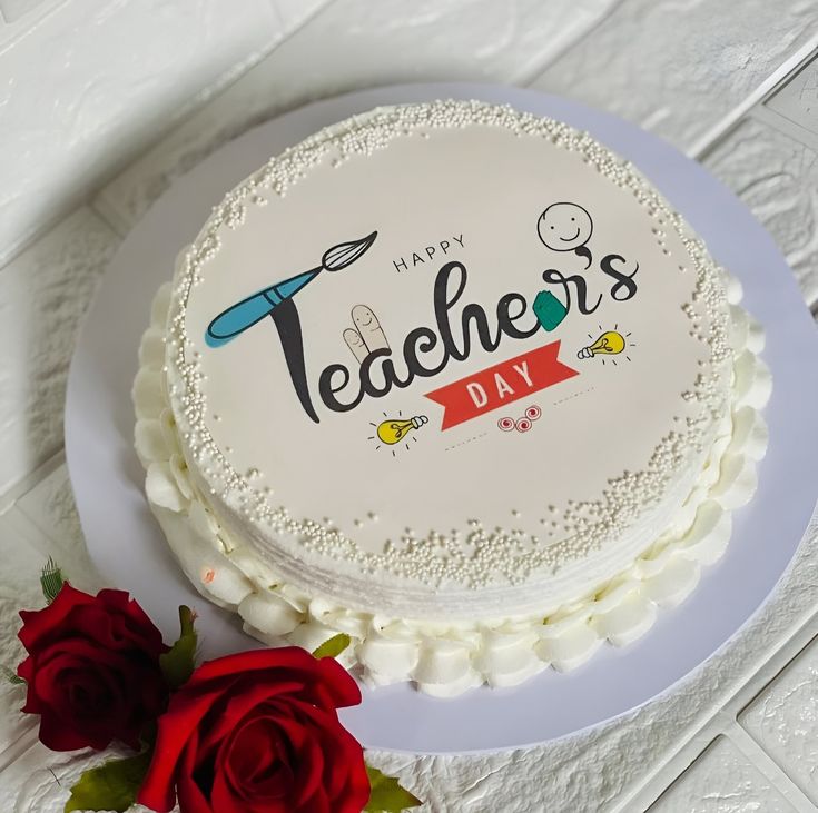 there is a white cake with the words teachers day on it and two red roses