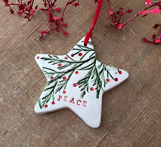 a ceramic christmas ornament hanging from a red ribbon on top of a wooden table