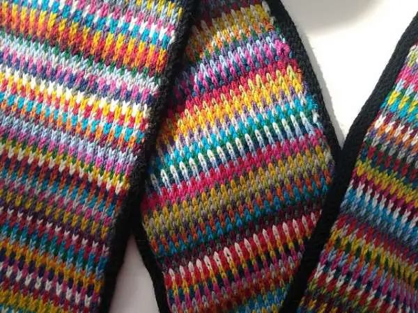 a multicolored knitted neck tie laying on top of a white surface