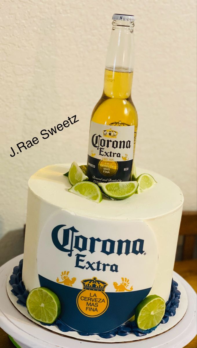 a cake with a beer bottle on top and limes around the edges, sitting on a table