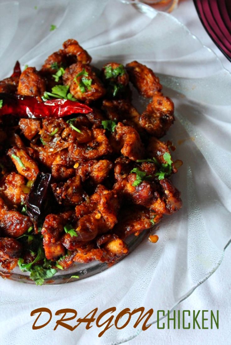 a plate full of food sitting on top of a white table cloth with the words dragon chicken above it