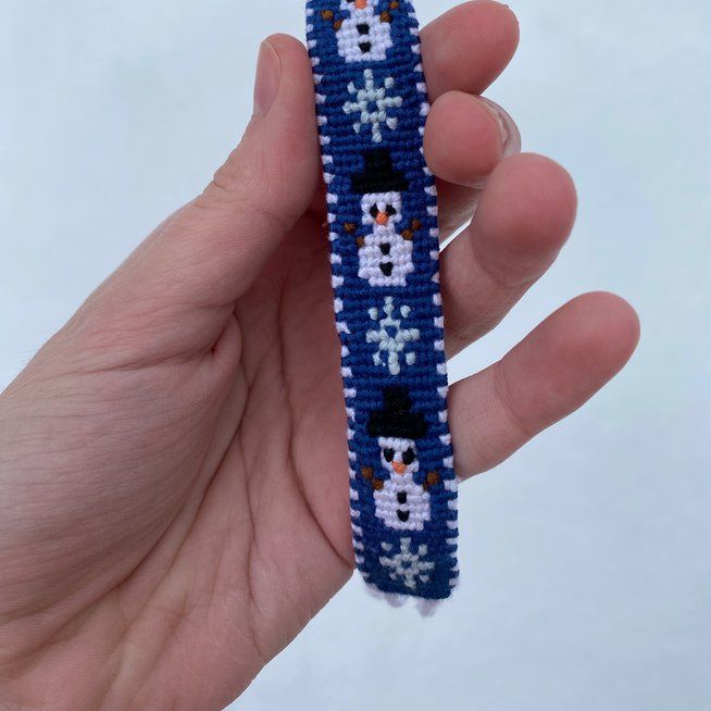 a hand holding a beaded bracelet in the shape of a skull and crossbones