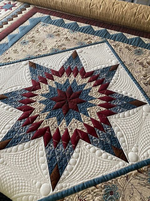 a quilted table topper with an intricate star design on it's center