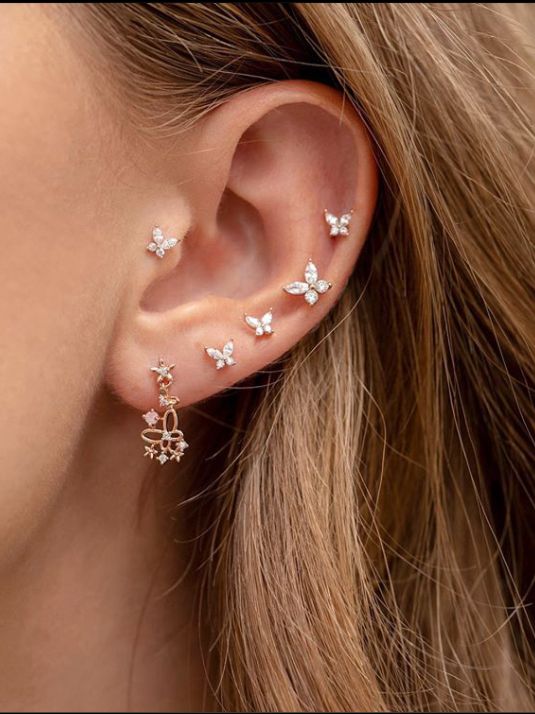 a woman's ear with three small white butterflies on it