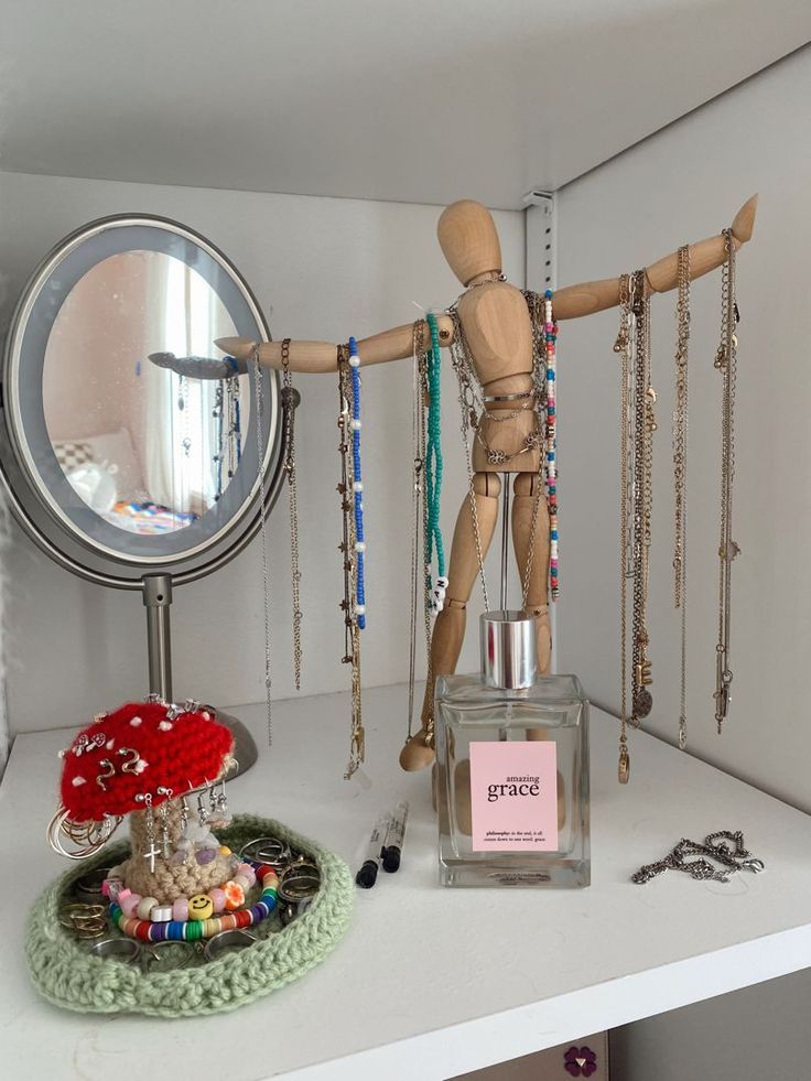 a wooden mannequin standing on top of a white shelf next to a mirror