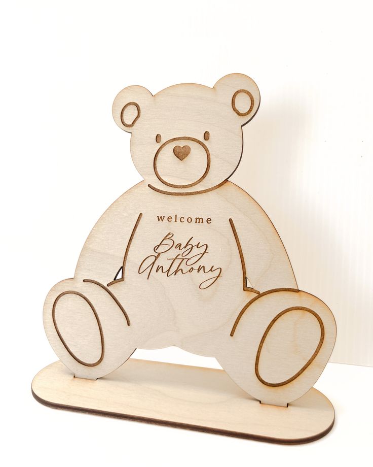 a wooden teddy bear sitting on top of a skateboard with the words welcome to baby anthony