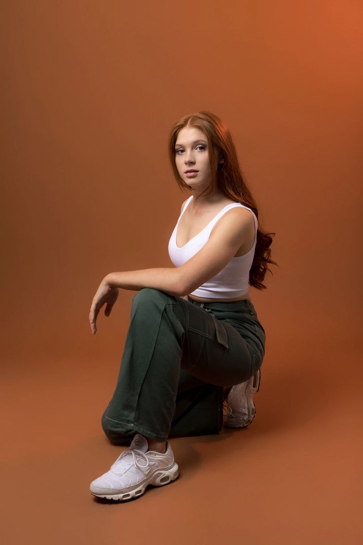 a woman is sitting on the ground with her legs crossed and looking at the camera