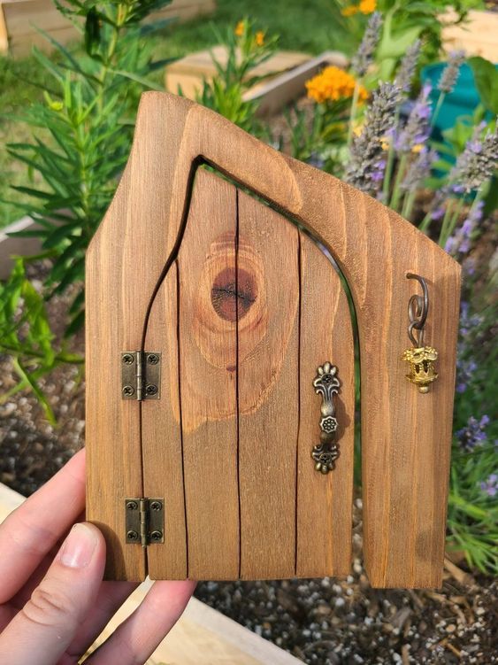 a hand holding up a small wooden house shaped like a hobbot door with key chains attached to it