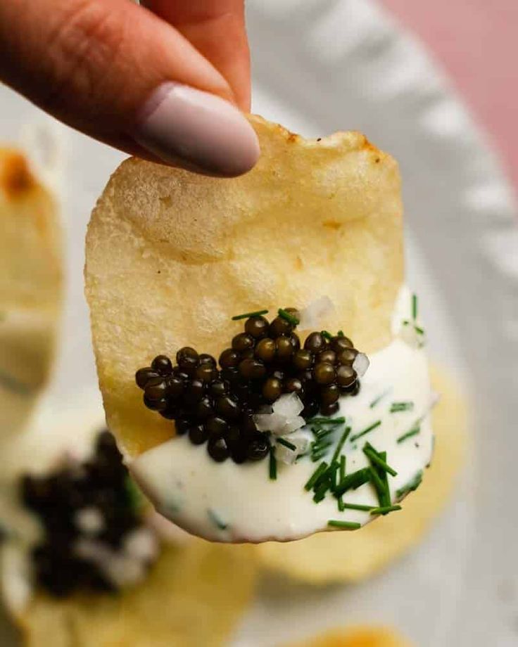 a hand holding a cracker with some sort of food on it