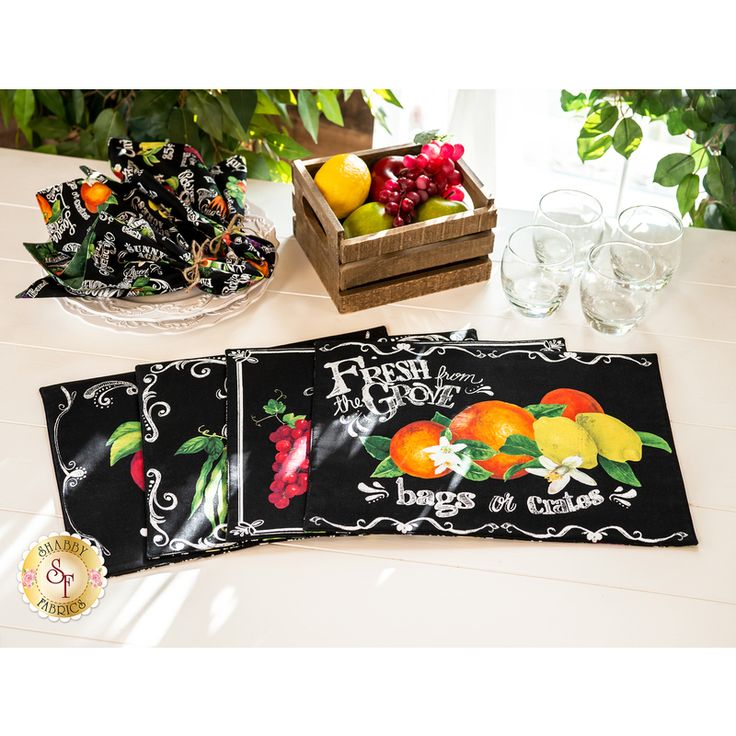 three placemats with fruit on them sitting on a table next to some glasses