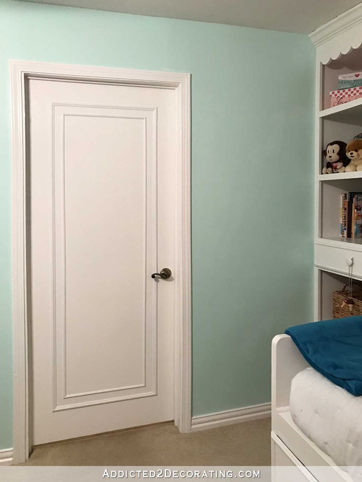 a bedroom with blue walls and a white door in the corner is empty except for bookshelves