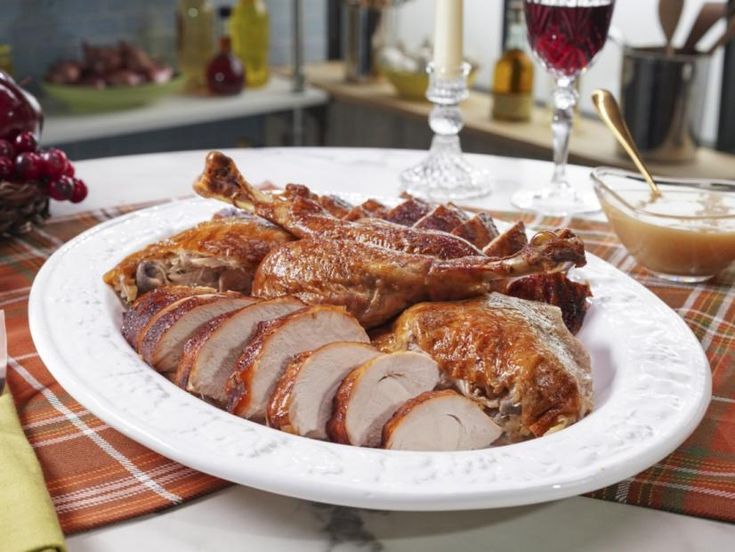 a white plate topped with sliced turkey next to a glass of wine