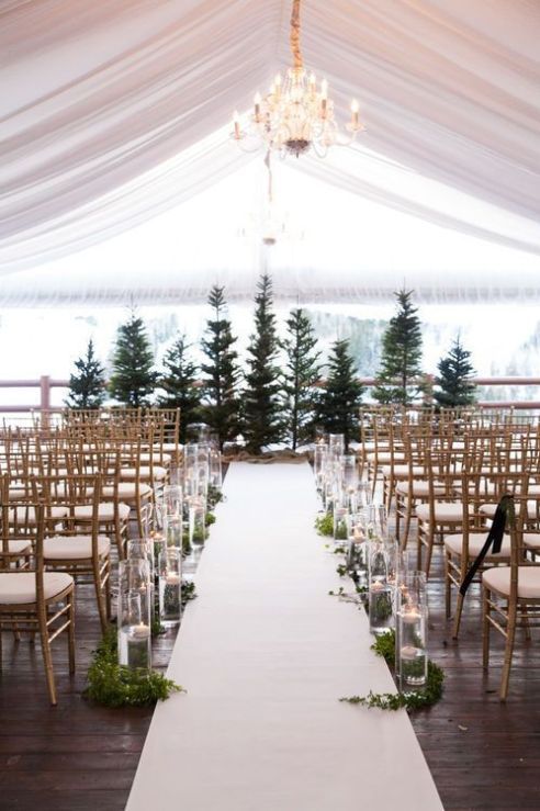 the aisle is lined with clear glass vases and greenery