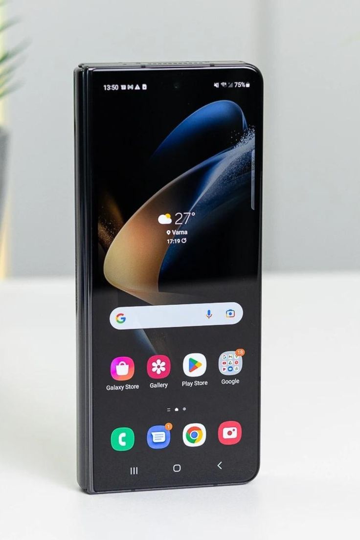 an image of a cell phone sitting on a white table with a potted plant in the background