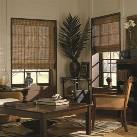 a living room filled with furniture and windows covered in bamboo blind shades on top of them