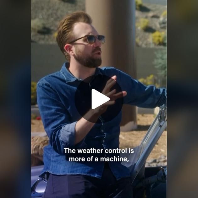 a man with glasses is talking to someone in front of a building and text that reads the weather control is more of a machine,