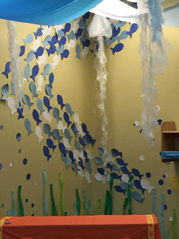 a baby crib in front of a wall decorated with blue and white paper fish