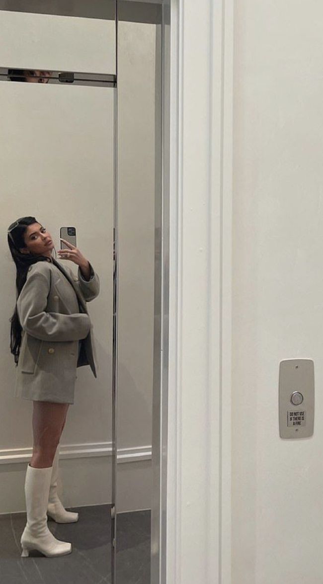 a woman taking a selfie in front of a mirrored wall with her cell phone