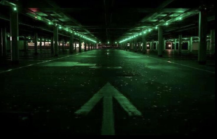 an empty parking garage at night with green lights