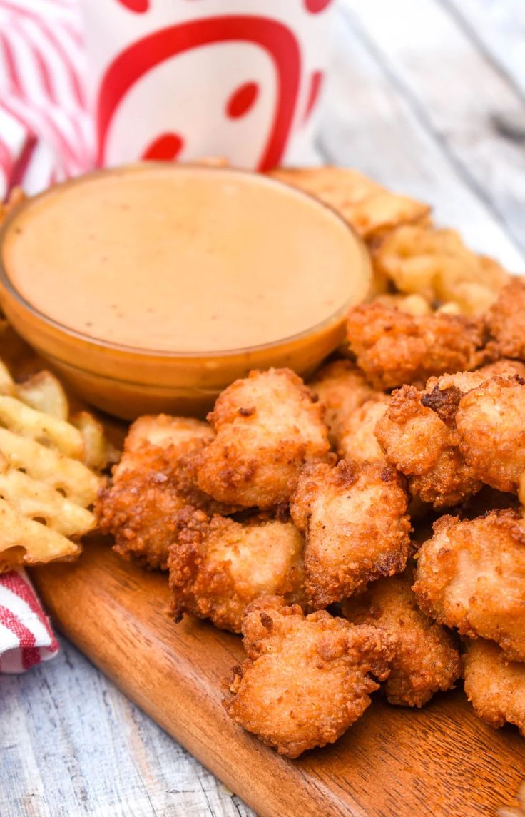 some fried food on a wooden board with a bowl of dipping sauce