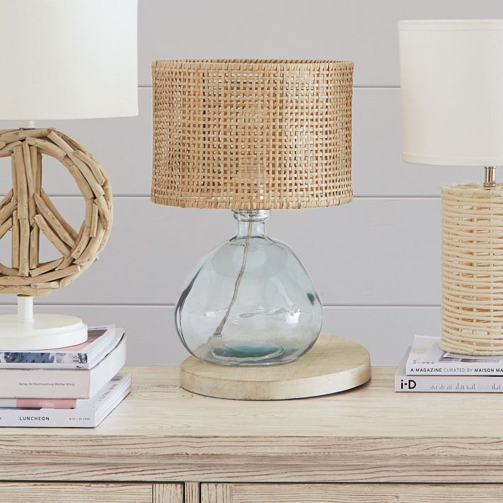 a table with two lamps on top of it next to books and a lamp shade