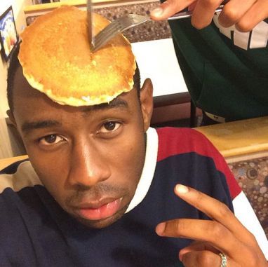 a man with a knife and fork on top of his head while he is cutting pancakes