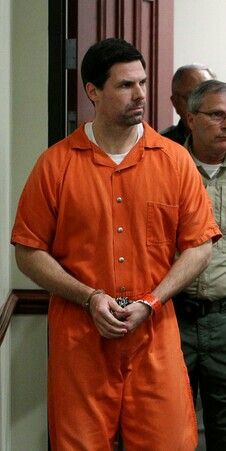 two men in orange prison uniforms standing next to each other