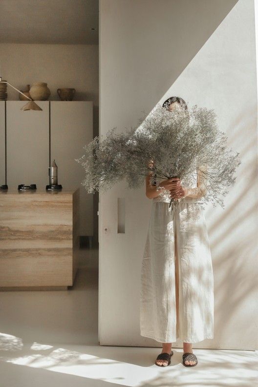 a woman in a white dress holding a bunch of flowers