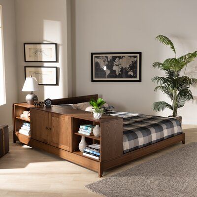 a bed sitting in a bedroom next to a wooden table with a potted plant on it