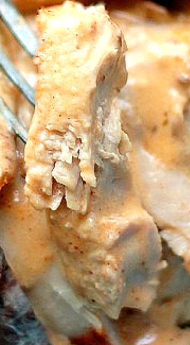 a close up of food on a fork with sauce and gravy in the background