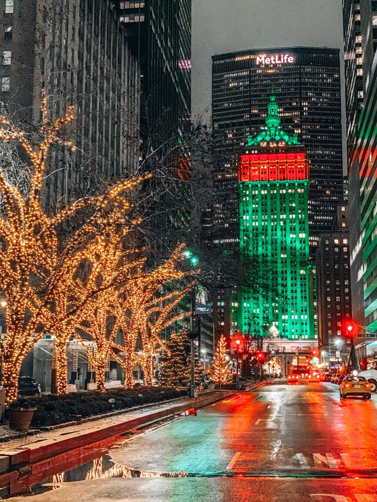 a city street at night with christmas lights on the trees and buildings in the background