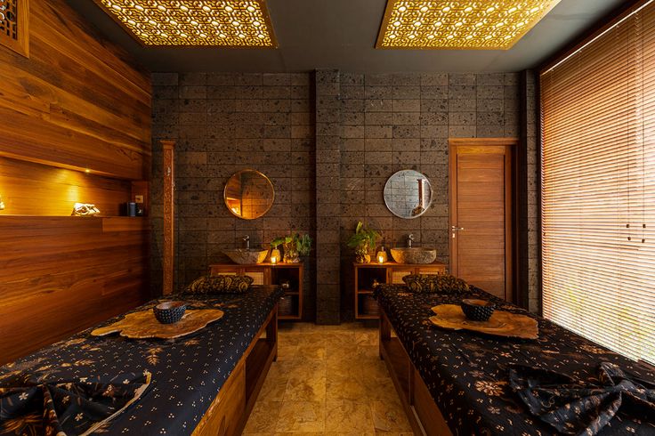 two beds in a room with wooden walls and lights on the ceiling, along with mirrors