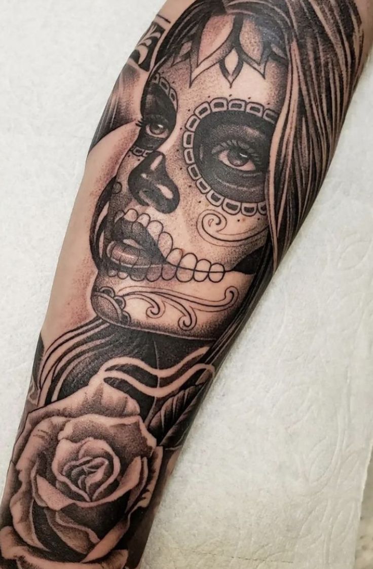 a woman with a skull and rose tattoo on her arm