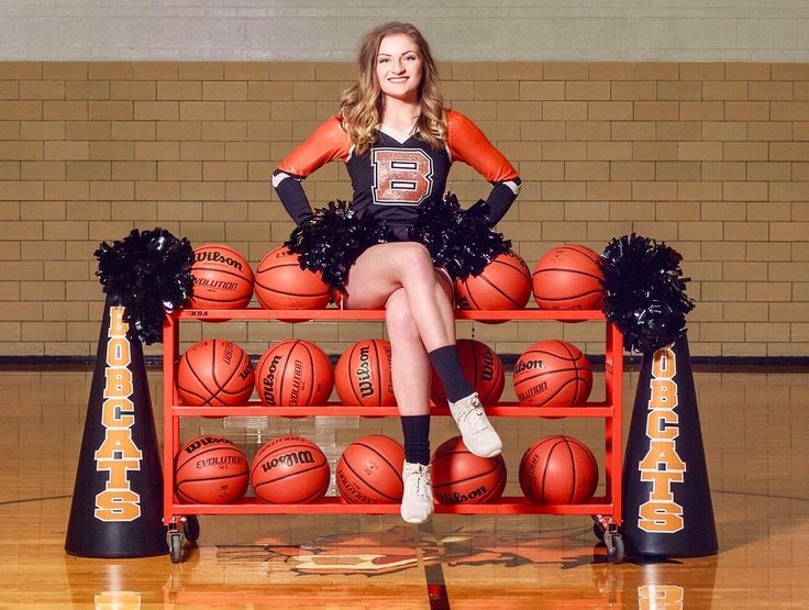 a cheerleader sitting on a bench with basketballs