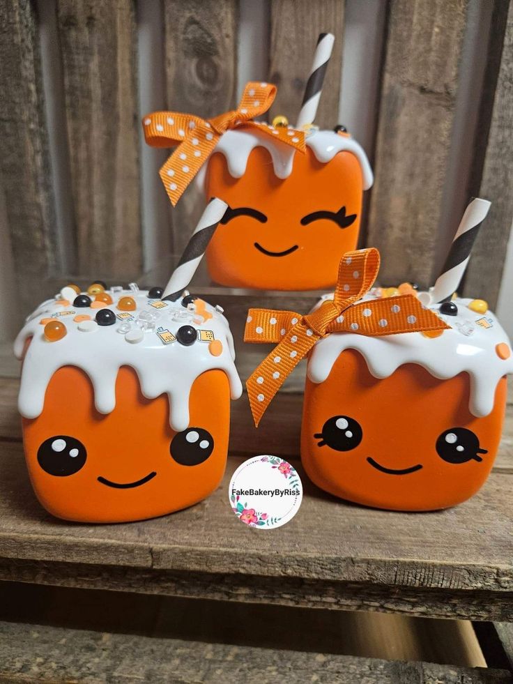 three orange and white pumpkins with faces painted on them, sitting on a wooden table