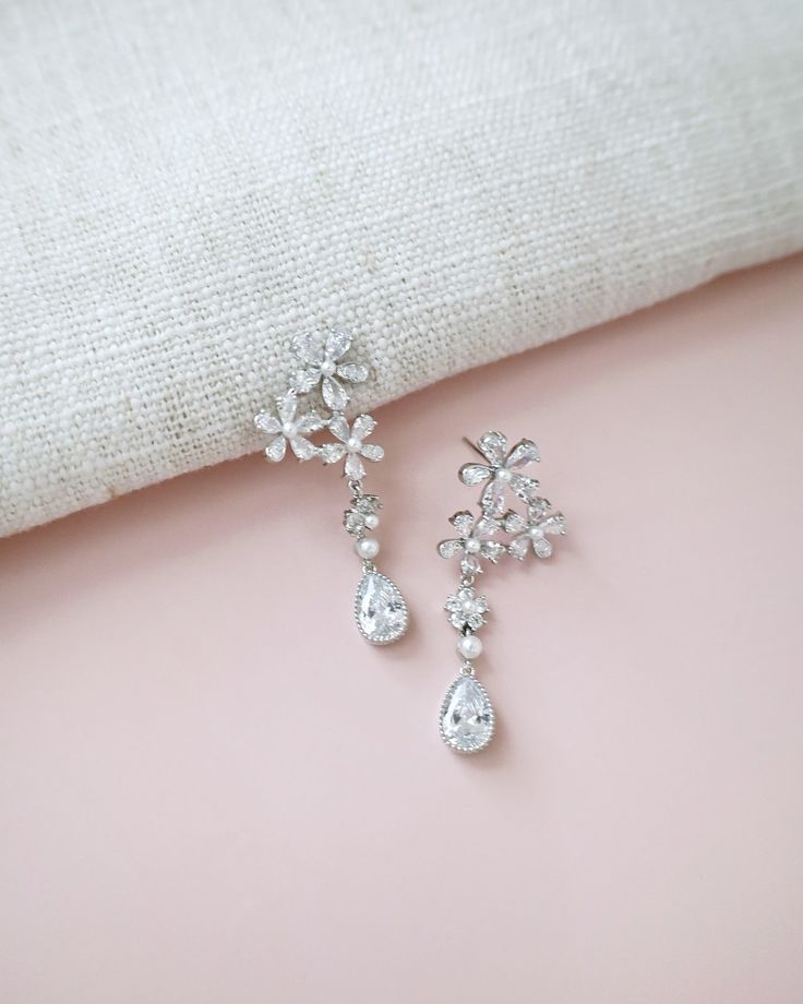 Delicate pear shape dangle earring seamlessly blend with floral rhinestones and accented with small pearls adds a classic touch for your ensemble. Pair them with an elegant dress for formal affair, or let them elevate your casual style. Perfect for date night, wedding, bridesmaids, holiday party, and any special occasions. DETAILS: LENGTH: 1.75"COLOR: SILVERIMPORTED MATERIALS Formal Pearl Embellished Drop Chandelier Earrings, Formal Pearl Embellished Chandelier Drop Earrings, Classic Flower Shaped Earrings For Wedding, Formal Dangle Flower Earrings With Cubic Zirconia, Elegant Pearl Embellished Dangle Chandelier Earrings, Elegant Crystal Flower Earrings For Party, Elegant Flower Earrings With Sparkling Stones For Wedding, Elegant Wedding Flower Earrings With Sparkling Stones, Elegant Crystal Embellished Bridal Earrings For Anniversary