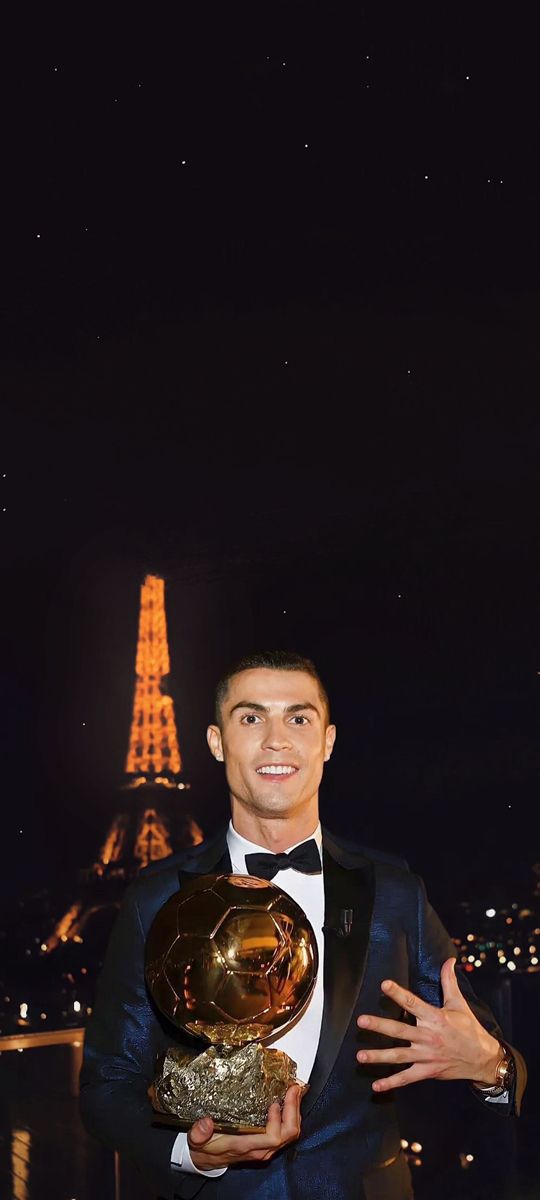 a man in a tuxedo holding a golden ballon d'or award