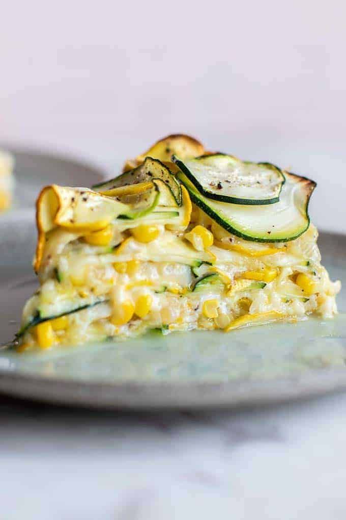 a slice of quiche with zucchini, corn and cheese on a plate